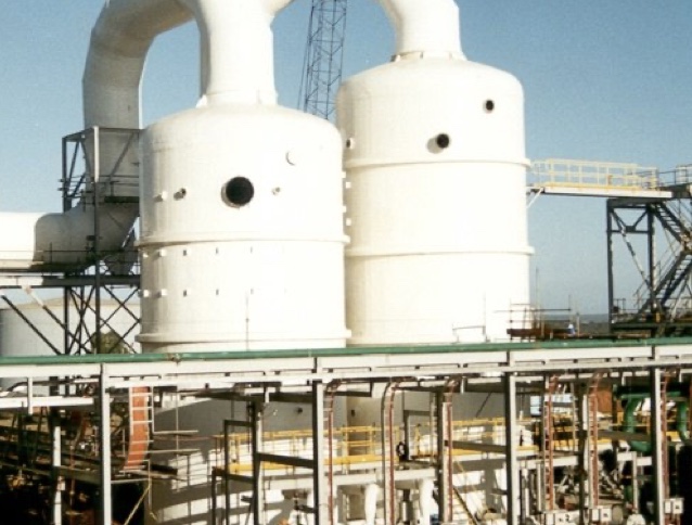 Twin white FRP scrubber vessels at an industrial plant